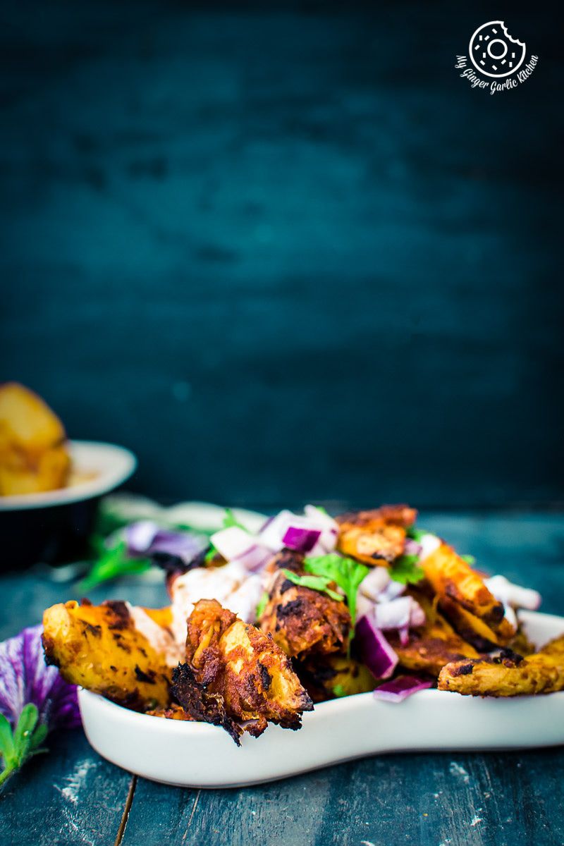 a plate of a plate of baked masala potato wedges with onions on it