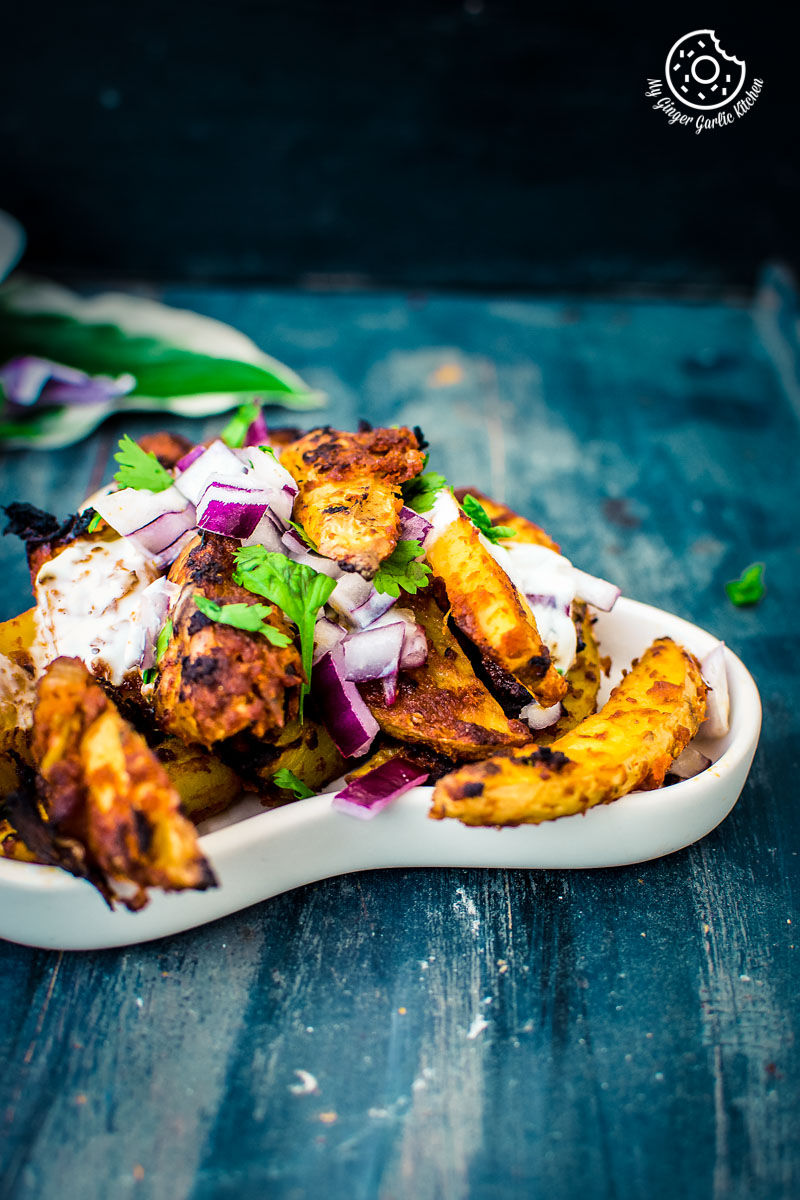 a plate of a plate of baked masala potato wedges topped with cilantro and onions