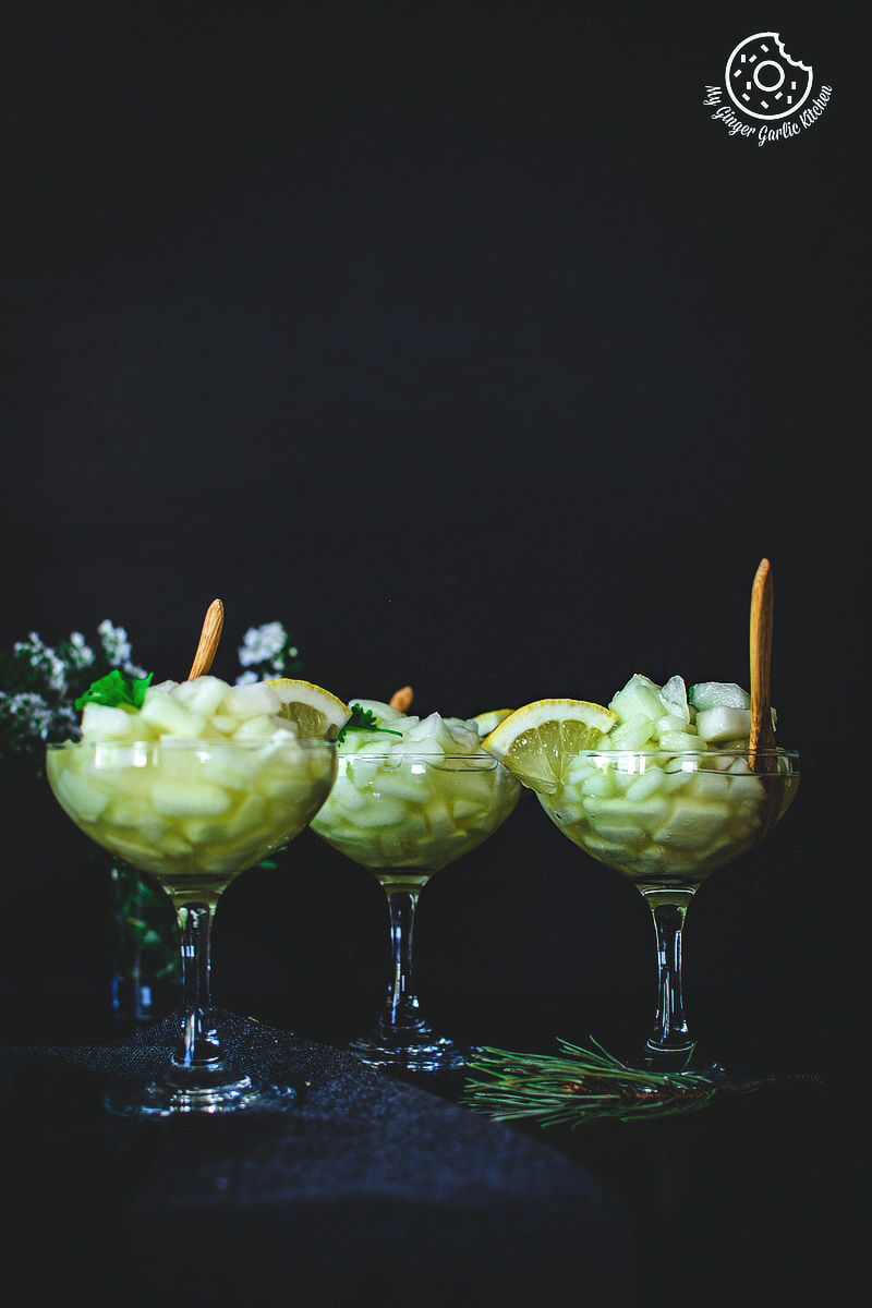 three glasses of kharbuje ka panna with a lemon slices and wooden spoon in them
