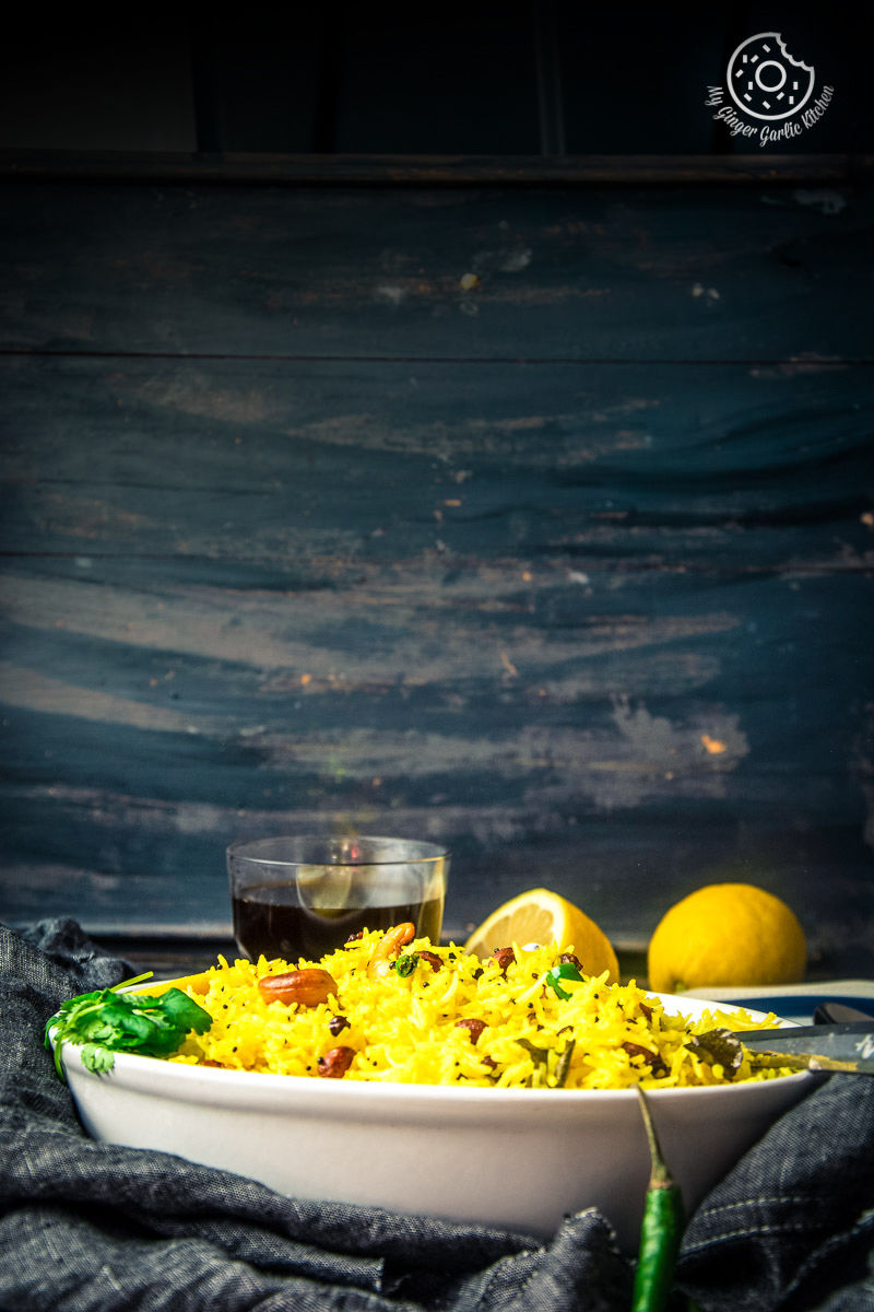 a plate of south indian lemon rice with lemons and a cup of coffee