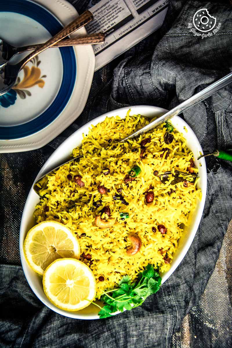 a bowl of south indian lemon rice with lemon slices and a spoon