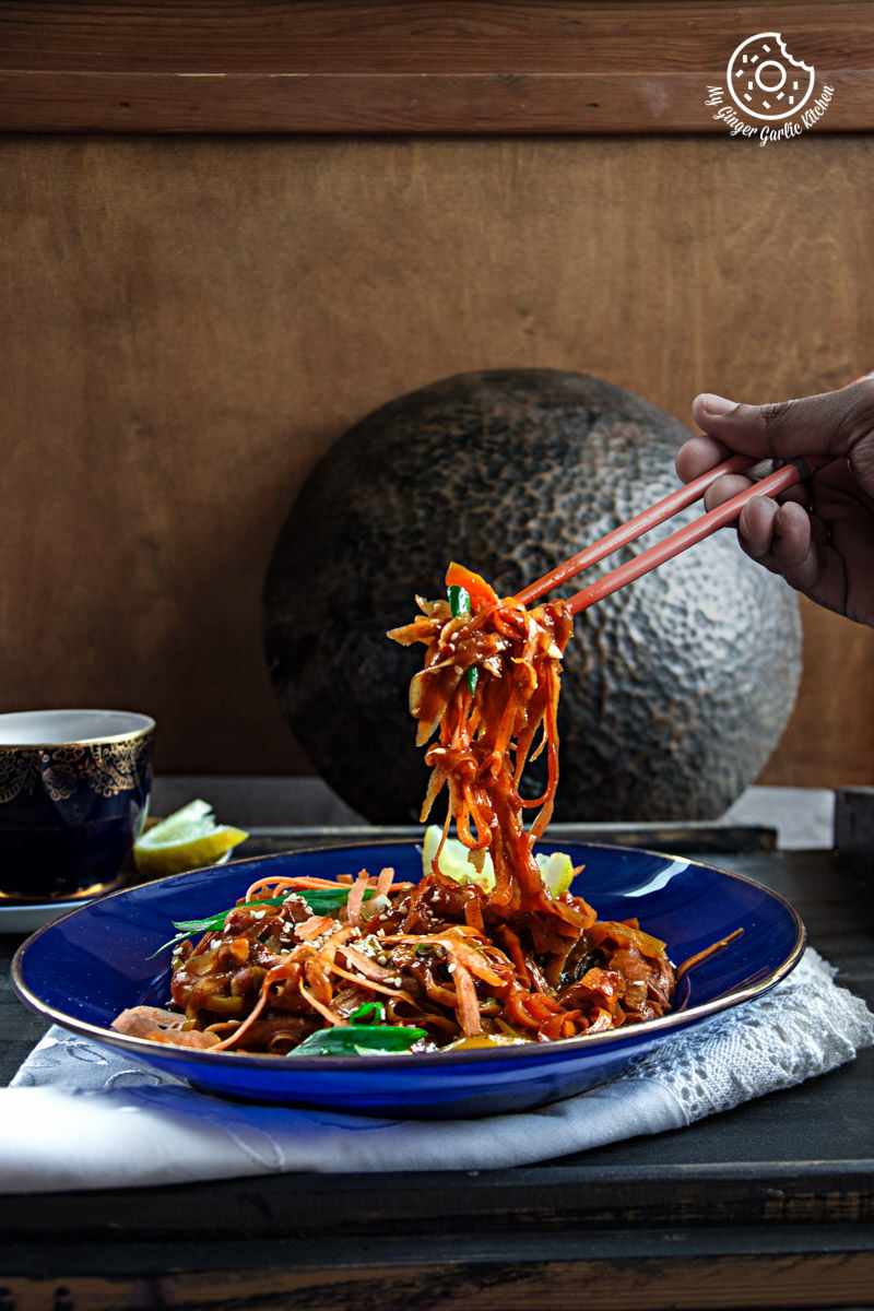 someone is holding chopsticks over a plate of szechuan spiced carrot fettuccine