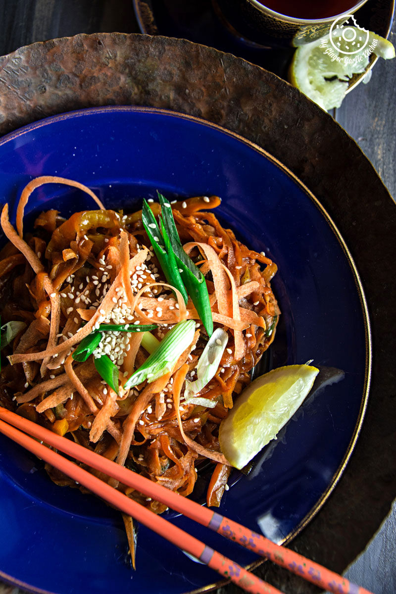 asian food with szechuan spiced carrot fettuccine and vegetables in a blue bowl