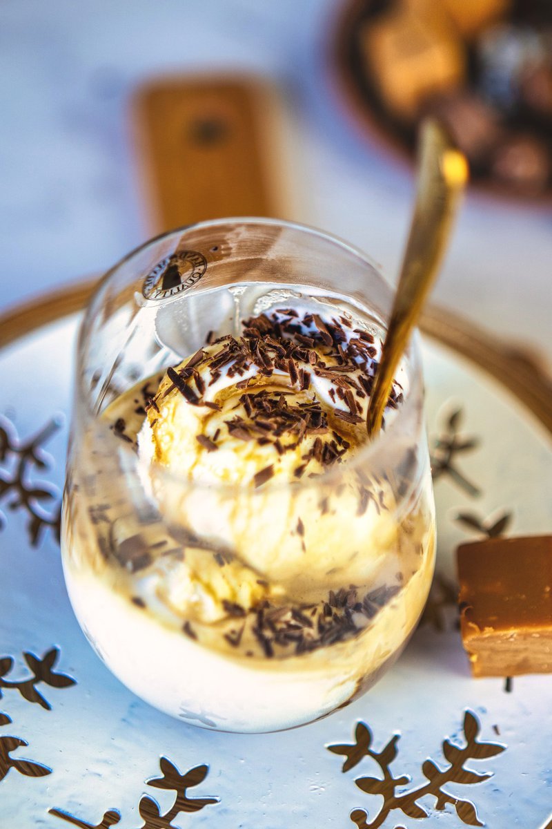 Close-up of affogato in a glass, showcasing scoops of vanilla ice cream drizzled with hot espresso and garnished with dark chocolate shavings.