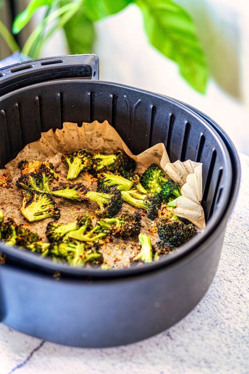 Crispy chili garlic air fryer broccoli in air fryer basket with roasted garlic, chili flakes, and crispy caramelized edges