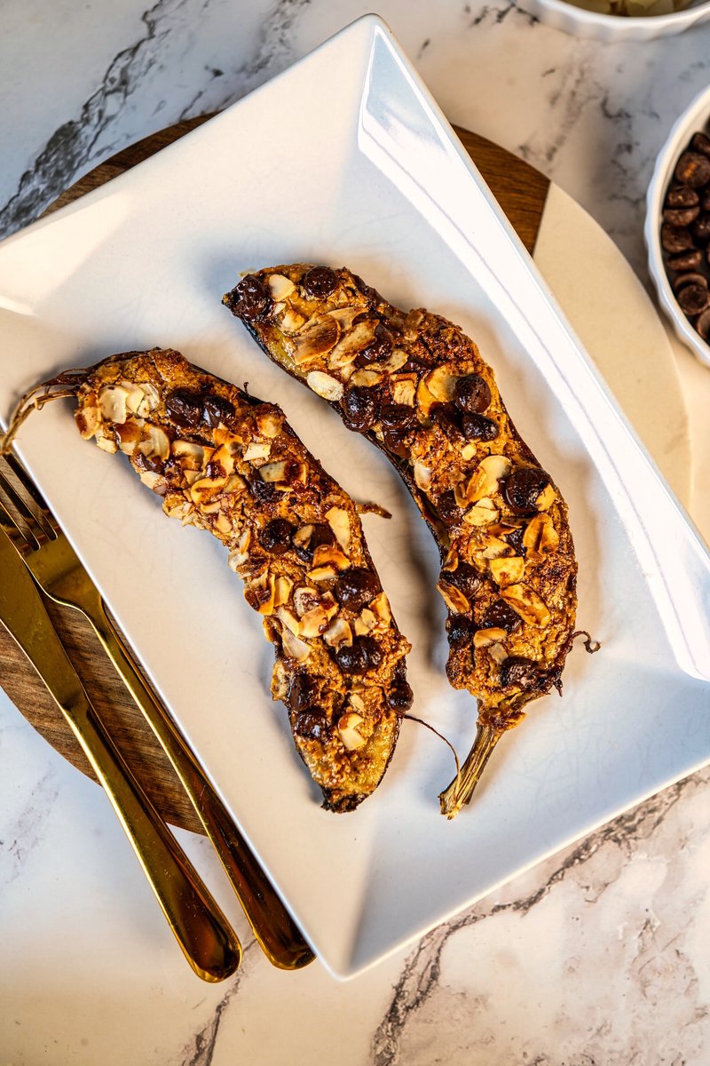Top view of homemade Air Fryer Banana with peanut butter, dark chocolate chips, and toasted almonds served on a white plate.