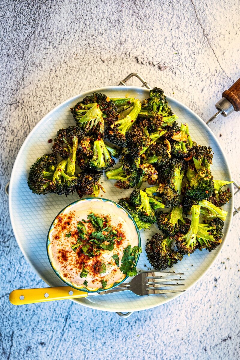 Crispy garlic butter air fryer broccoli served with creamy yogurt sriracha dip on a plate