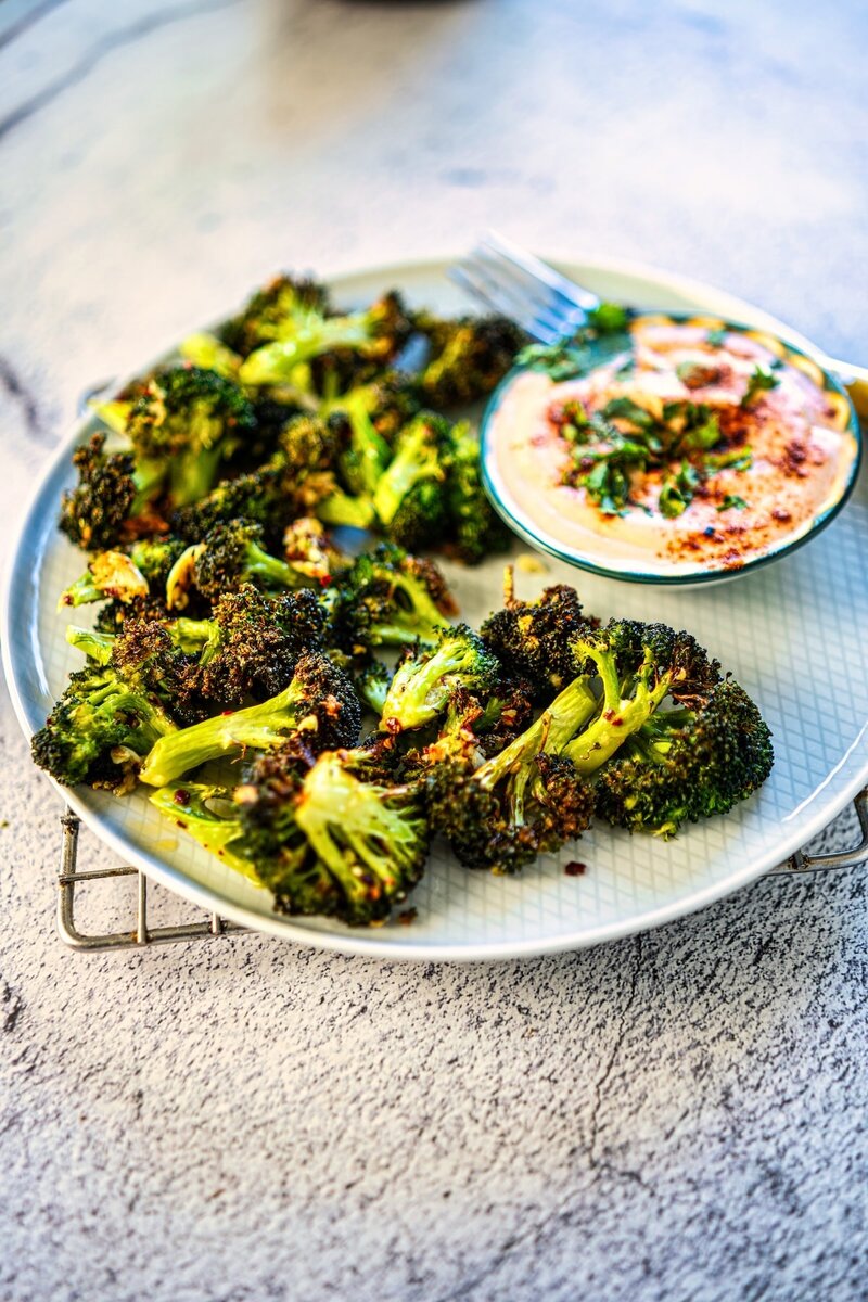 Crispy air fryer broccoli with garlic butter and chili flakes served with creamy spicy yogurt dip