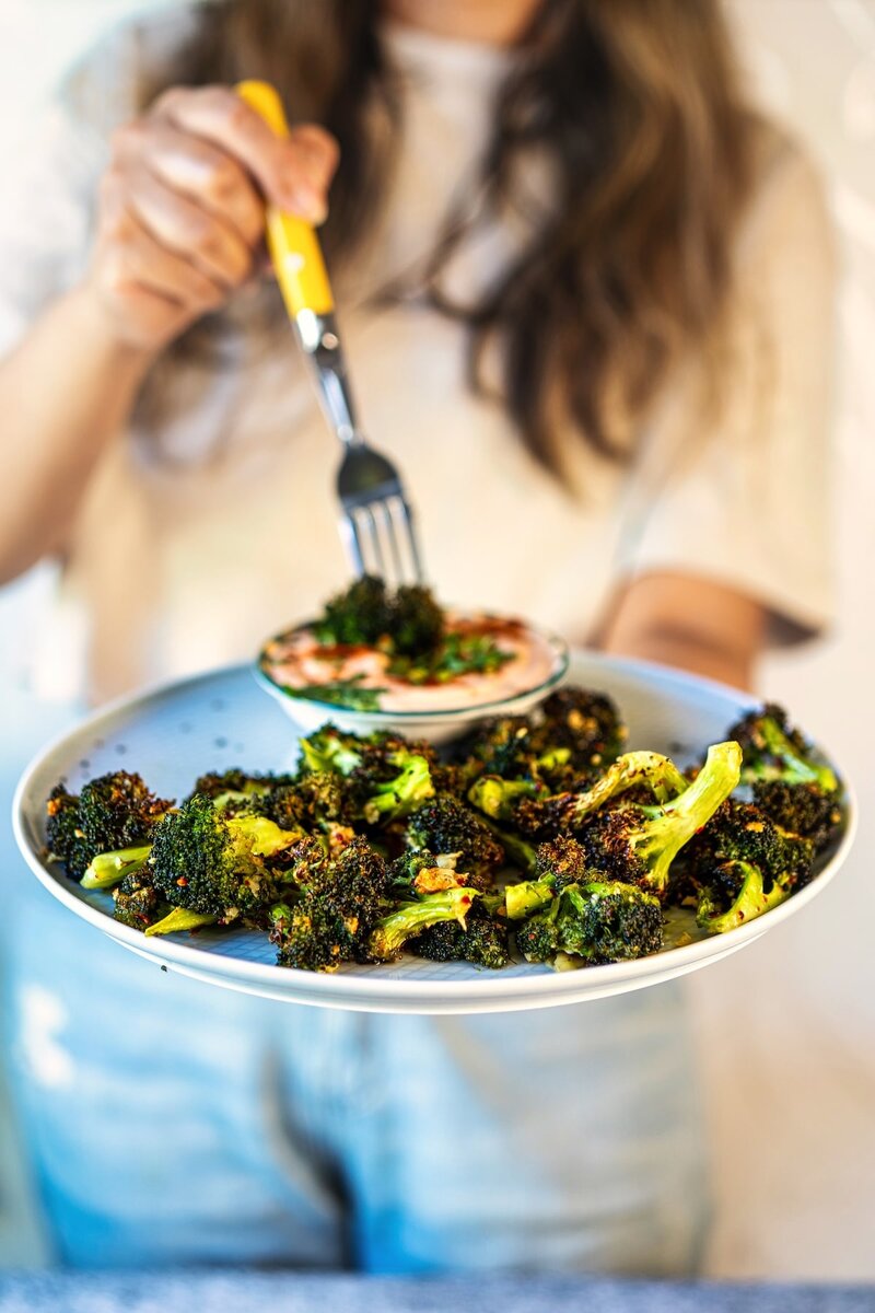 Crispy chili garlic air fryer broccoli served with creamy yogurt dip and roasted garlic pieces on plate