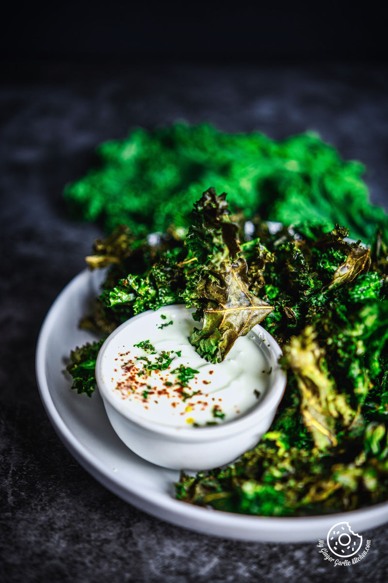 close-up of a plate of air fryer kale chips with a dip bowl