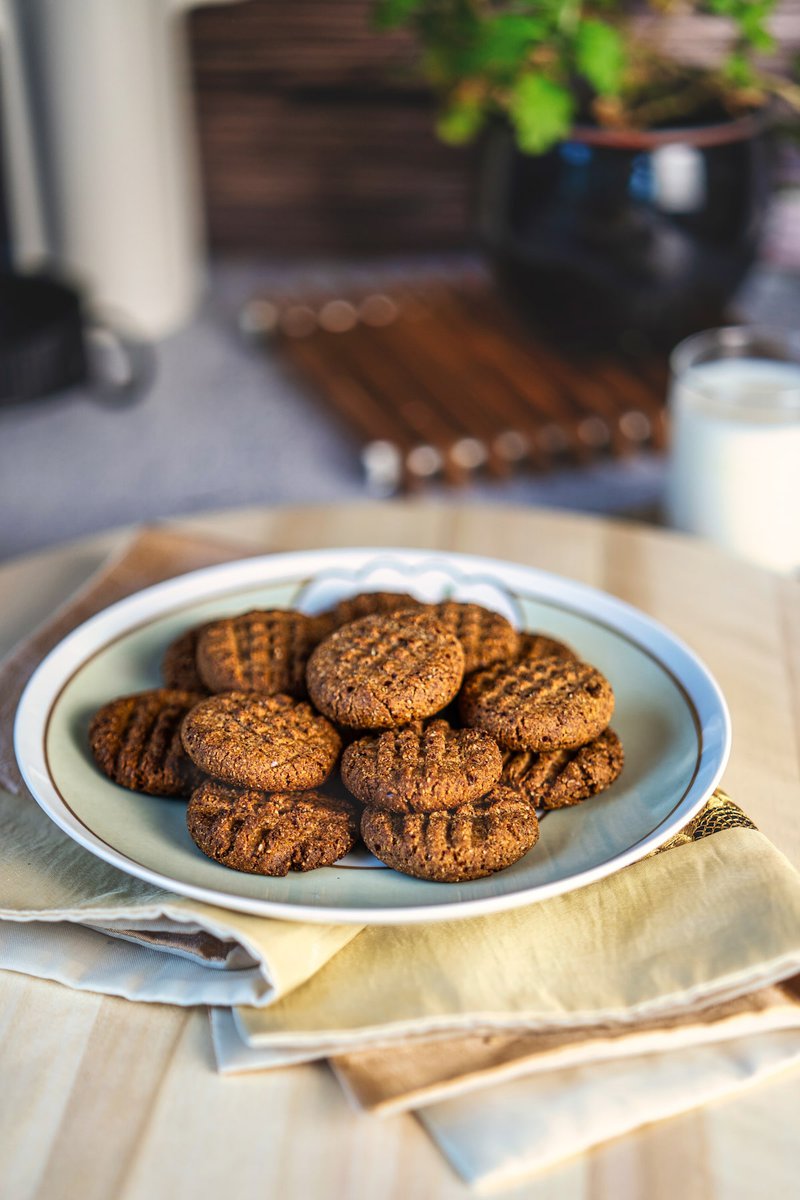 A plate of freshly baked almond date cookies stacked on a light-colored napkin on a wooden table.