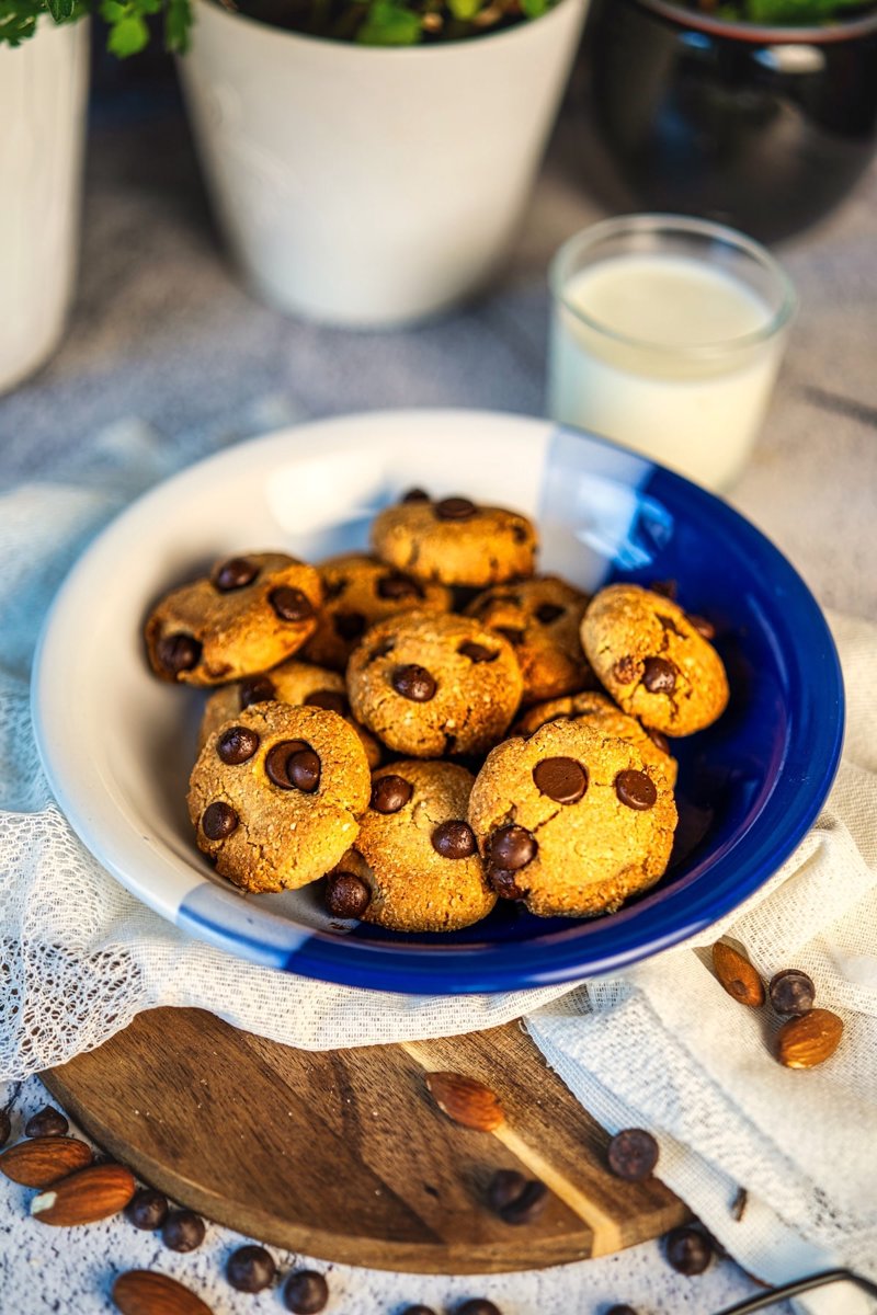 Almond flour tahini chocolate chip cookies in a blue and white bowl, served with a glass of milk.