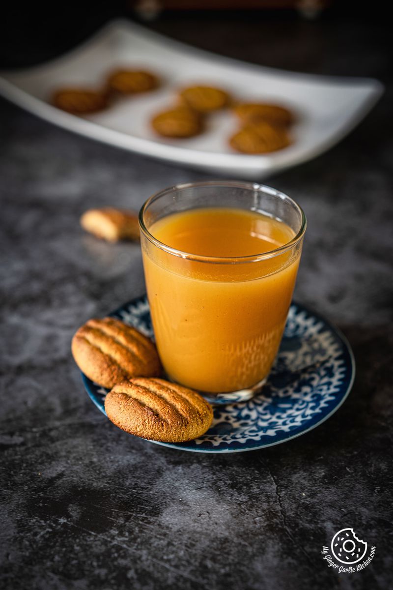 two almond flour cookies in a blue plate with a glass of orange juice
