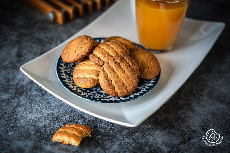 almond flour cookies in a blue plate with a glass of orange juice