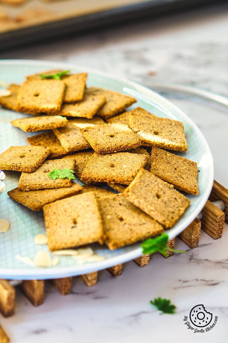 a closeup shot almond flour crackers in a plate with dip on the side