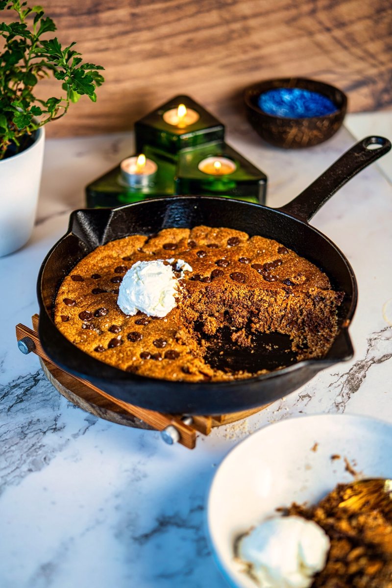 Vegan almond flour chocolate chip skillet cookie with a crisp golden top, soft fudgy center and vanilla ice cream.