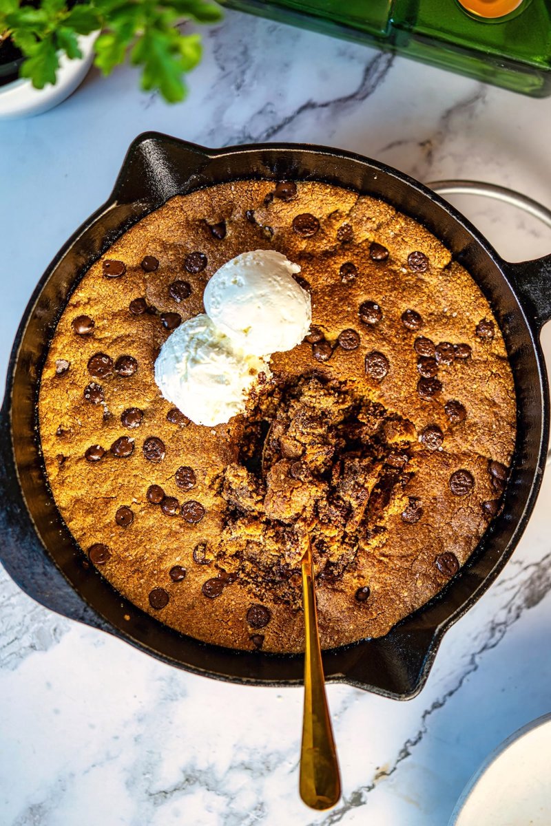 Warm almond flour chocolate chip skillet cookie topped with vanilla ice cream and dark chocolate chips.