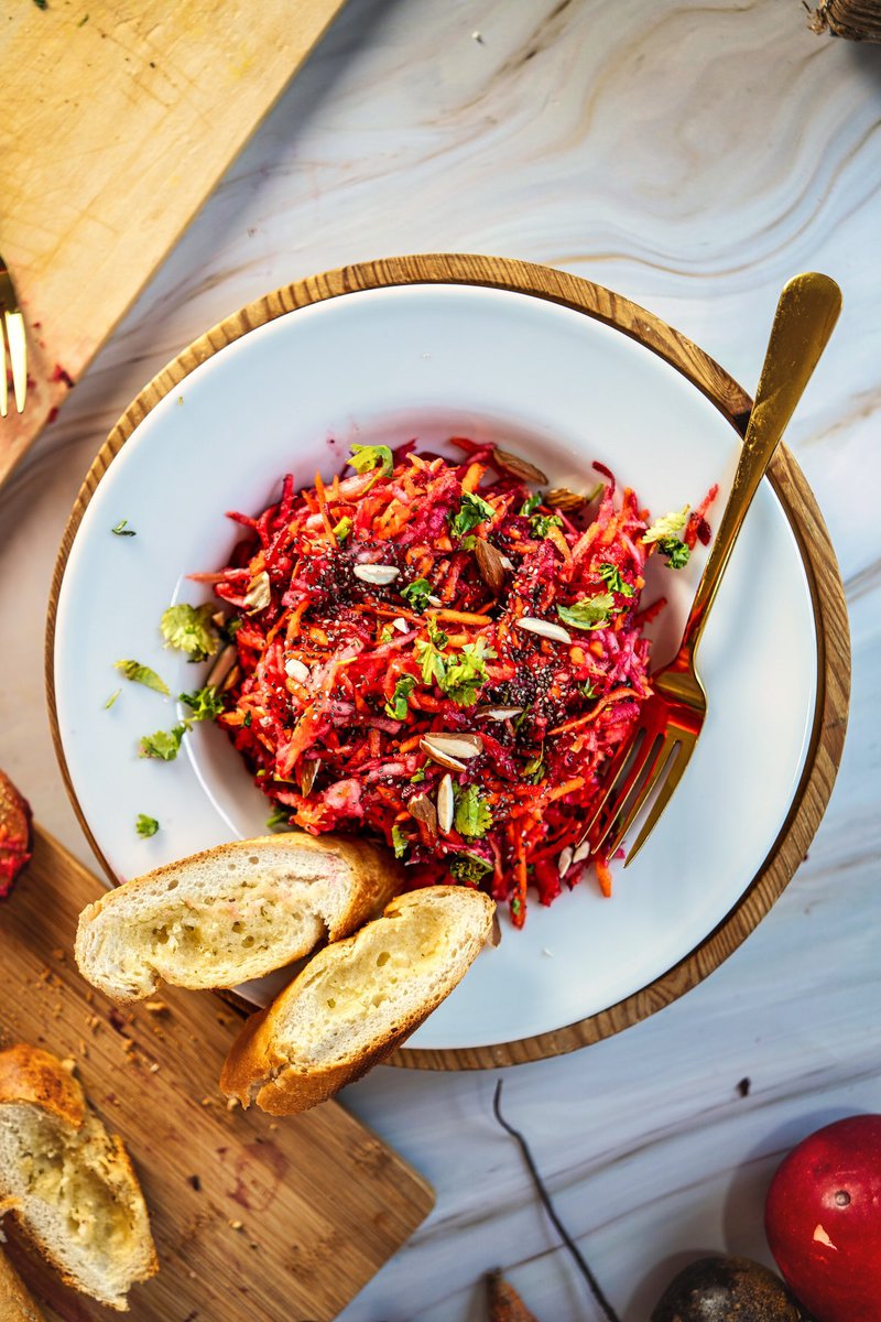 Top view of a colorful apple beetroot carrot salad with fresh herbs and bread slices for a nutritious dish.