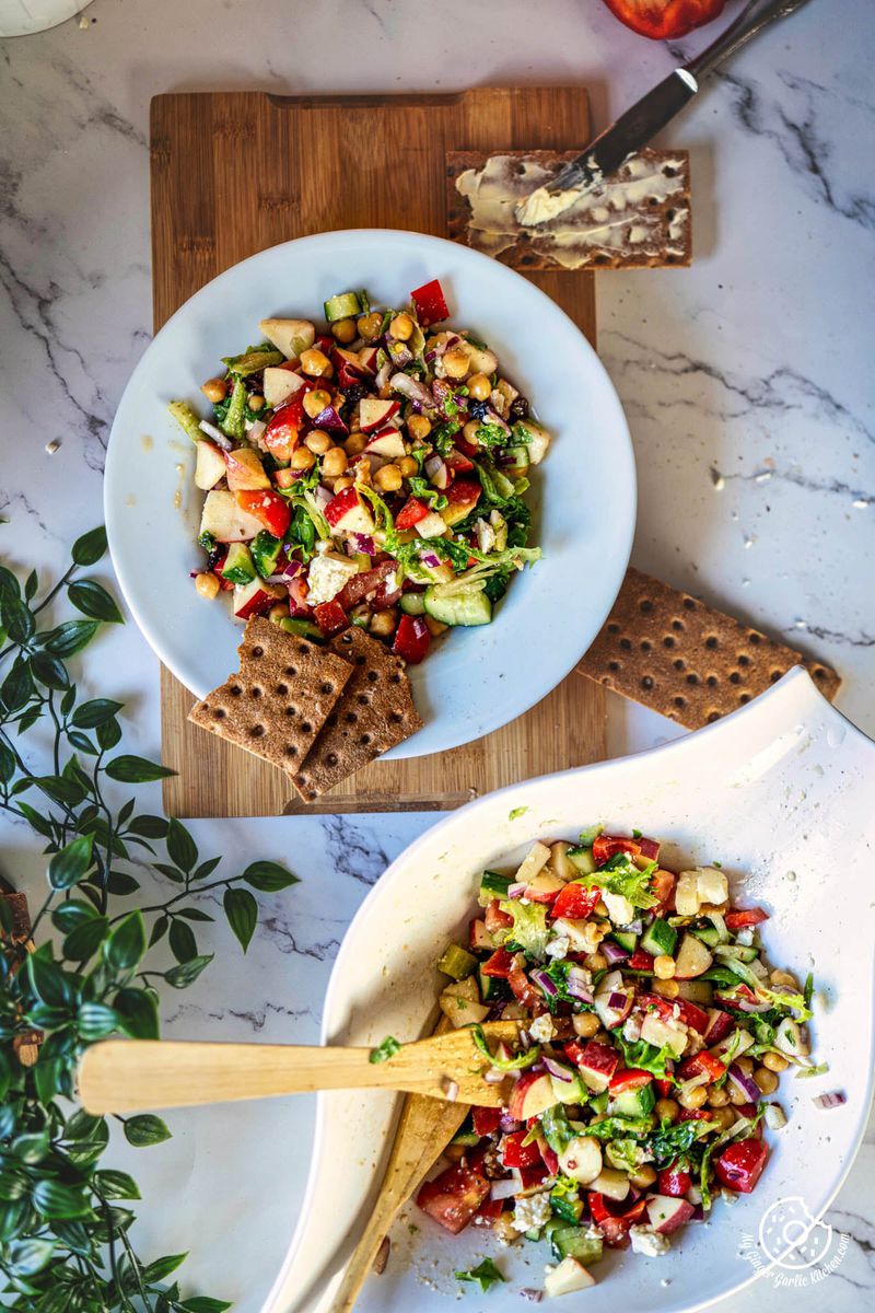 two bowls of apple salad on a table with a knife and crackers next to them