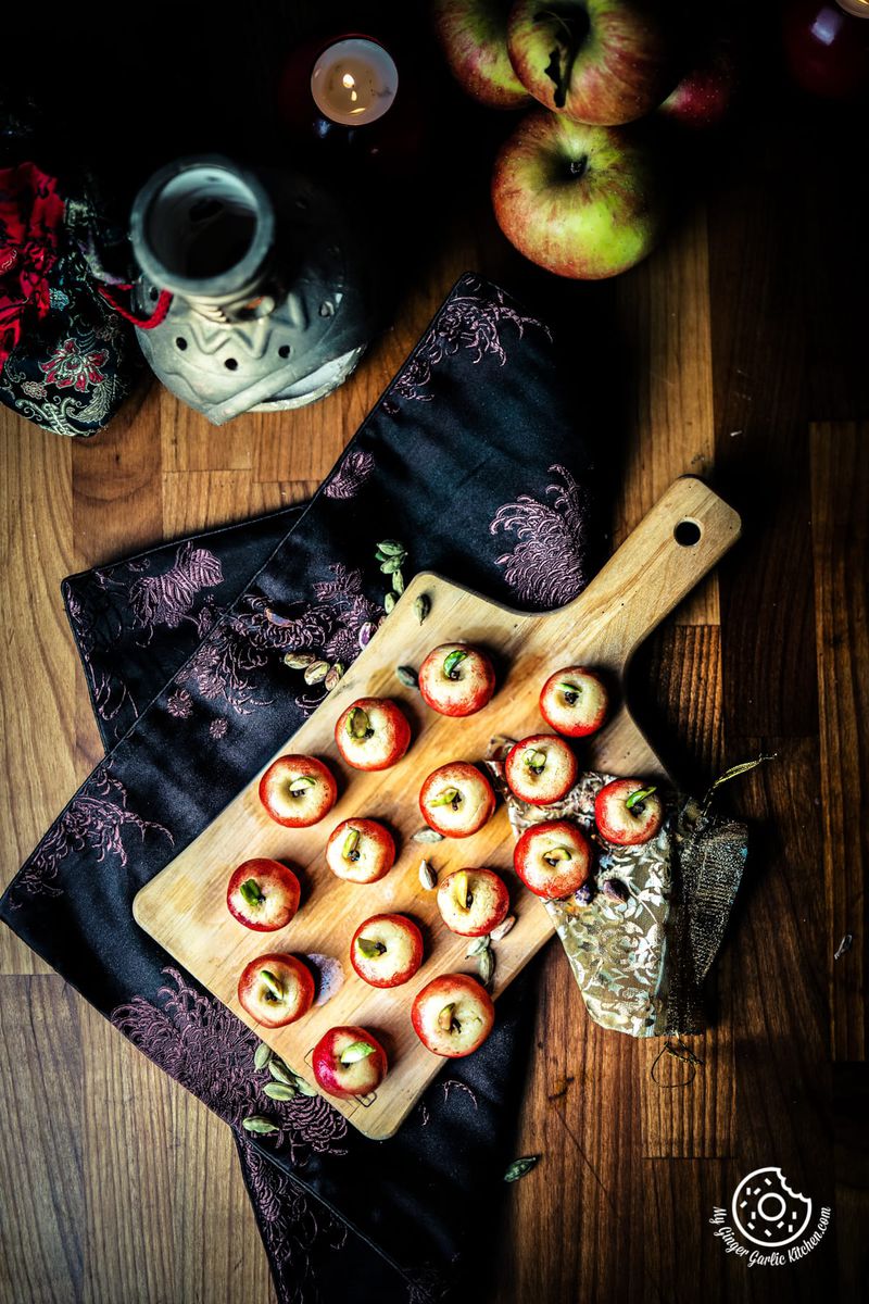 overhead shot of milk peda served on a wooden cutting board and apples on the side