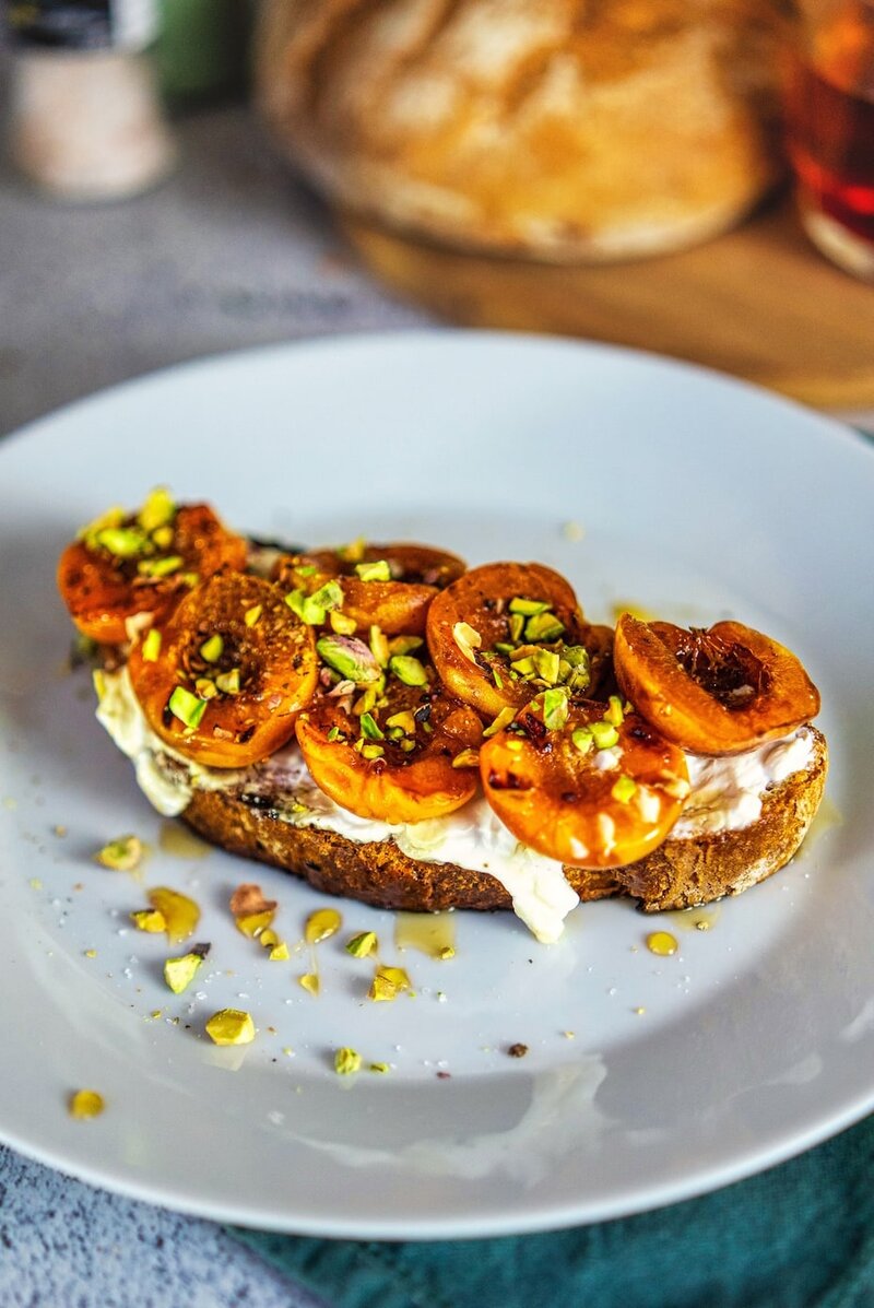 Healthy grilled apricot toast with whipped cottage cheese and pistachios served on sourdough breakfast toast
