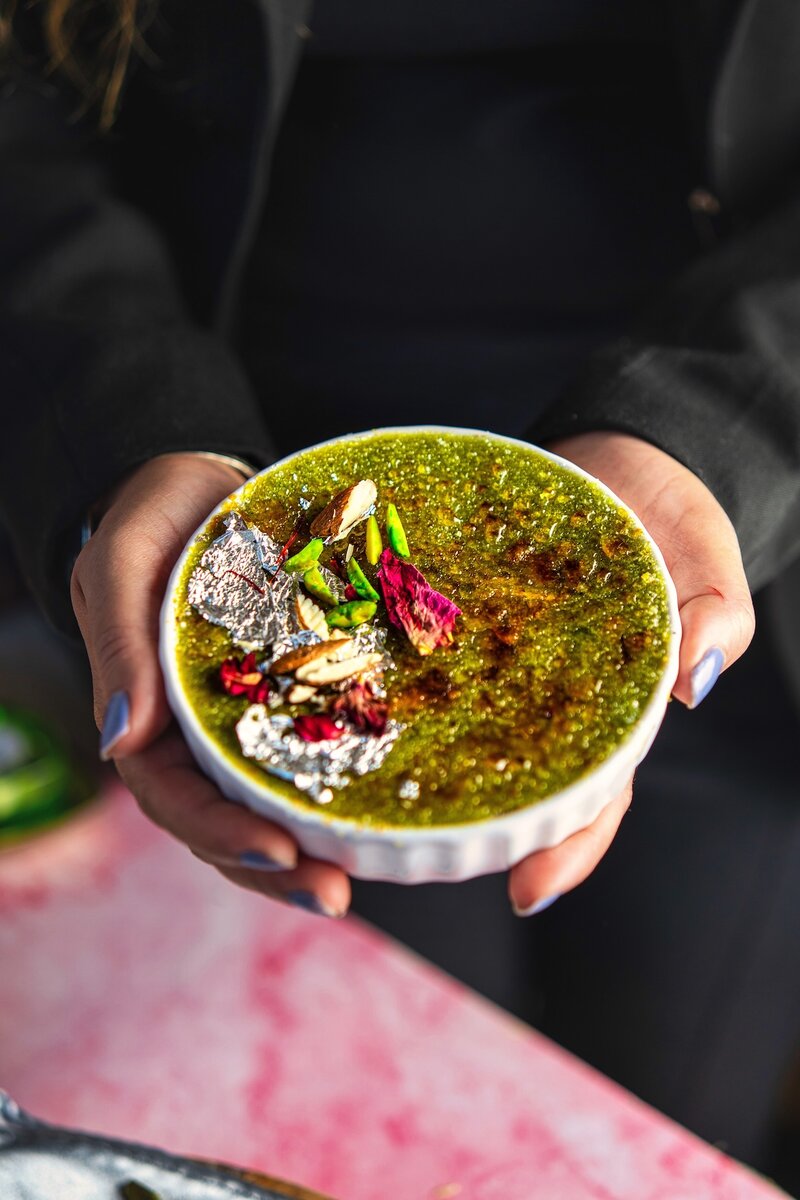 Avocado burfi brûlée with rich caramelized top and festive garnish of nuts, saffron, and edible silver leaf