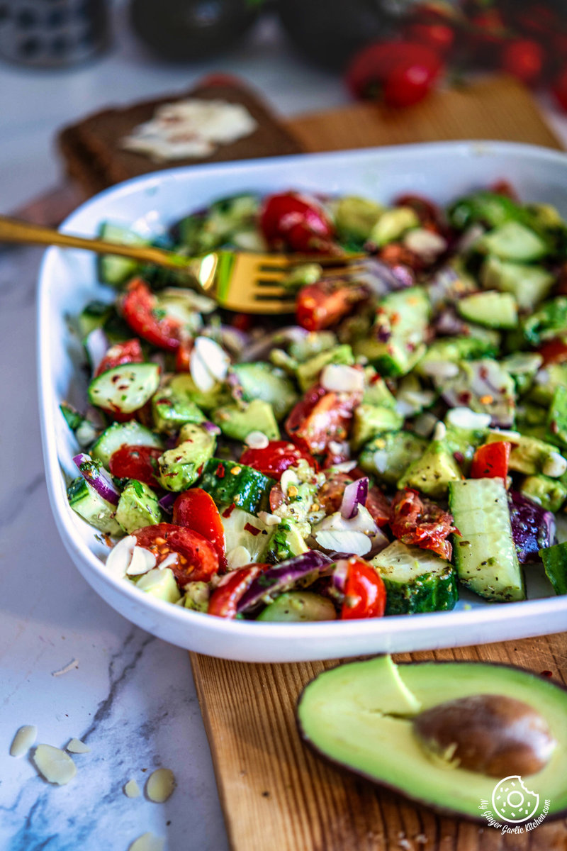 a white bowl filled with fresh and creamy avocado salad and a fork