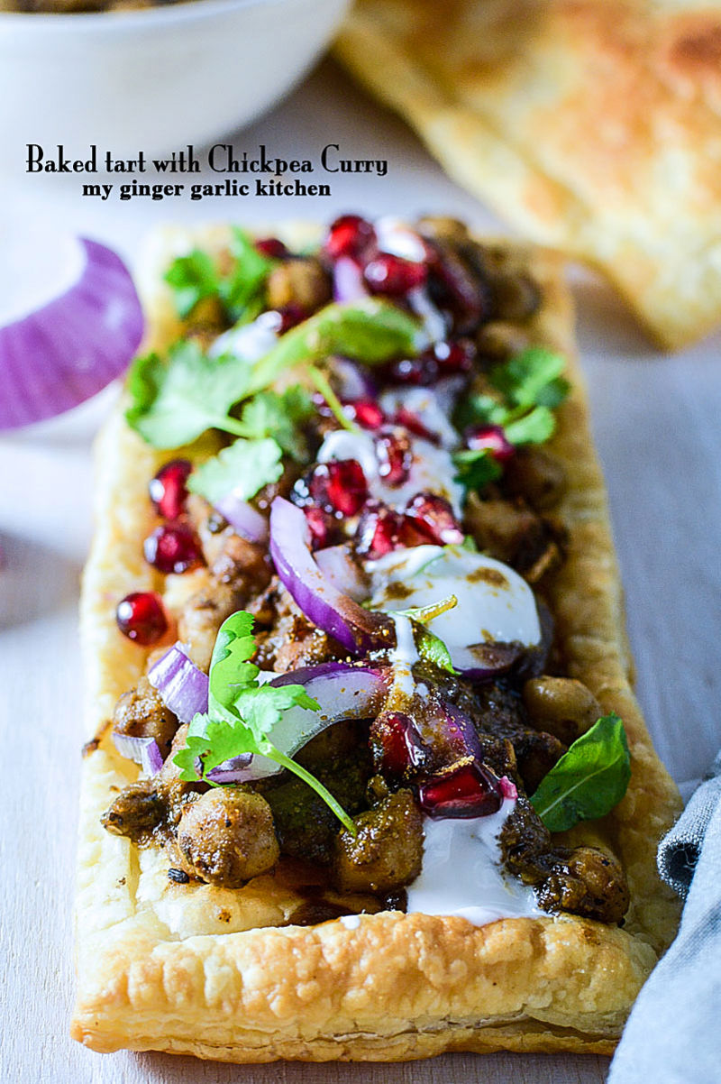 a baked tart with chickpeas curry and tamarind chutney with chickpeas, onions, and pomegranate on it