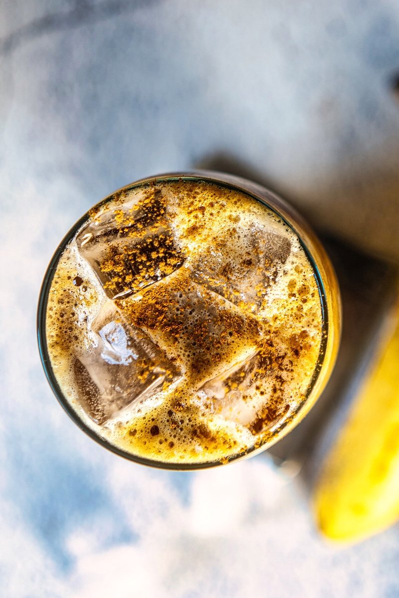 Banana iced latte topped with cinnamon and ice, photographed from above