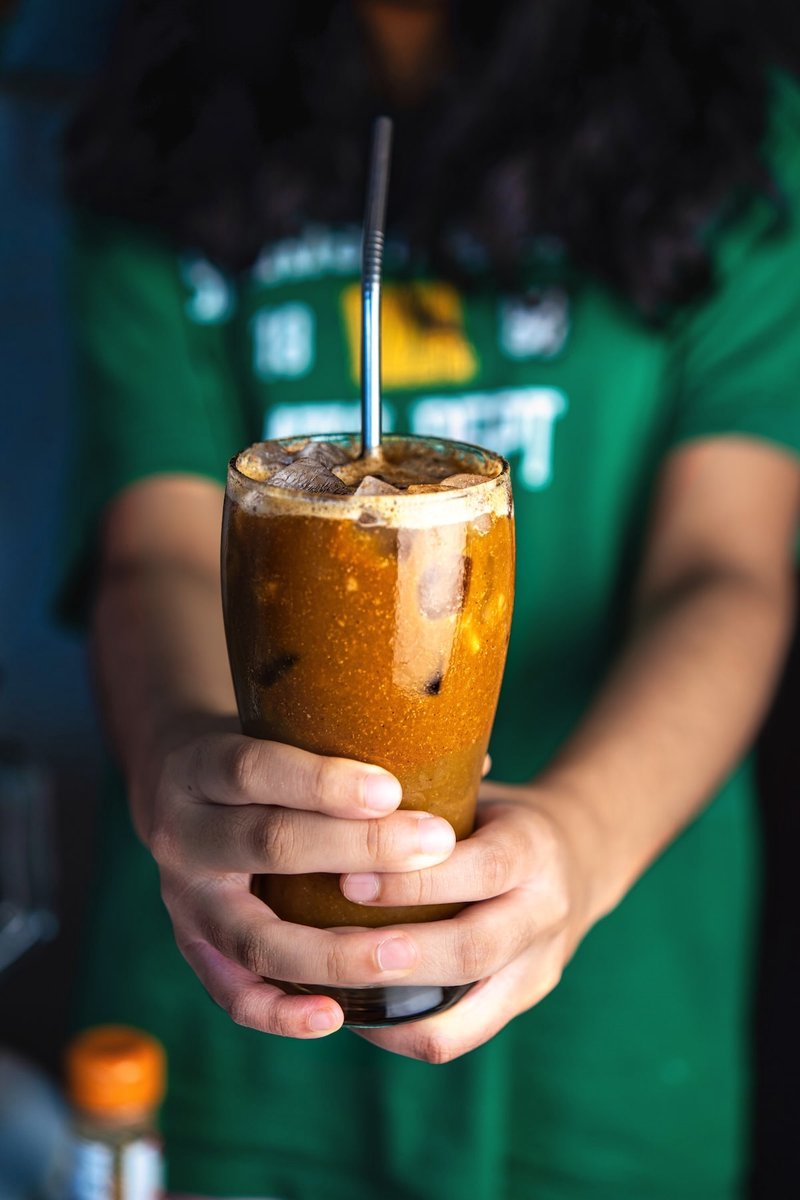 Banana iced latte held in a glass with a straw