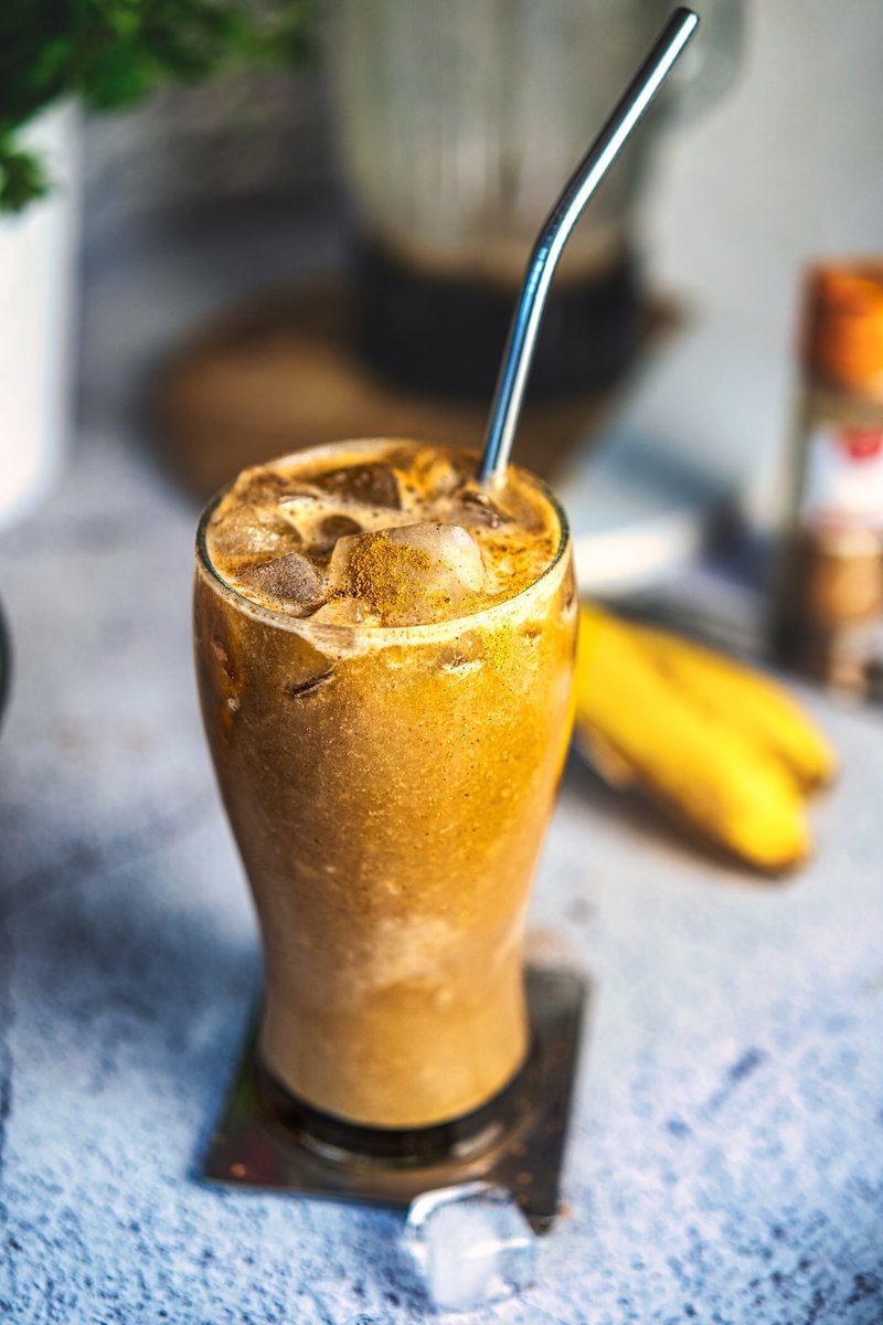 Close-up of a creamy banana iced latte with ice and cinnamon