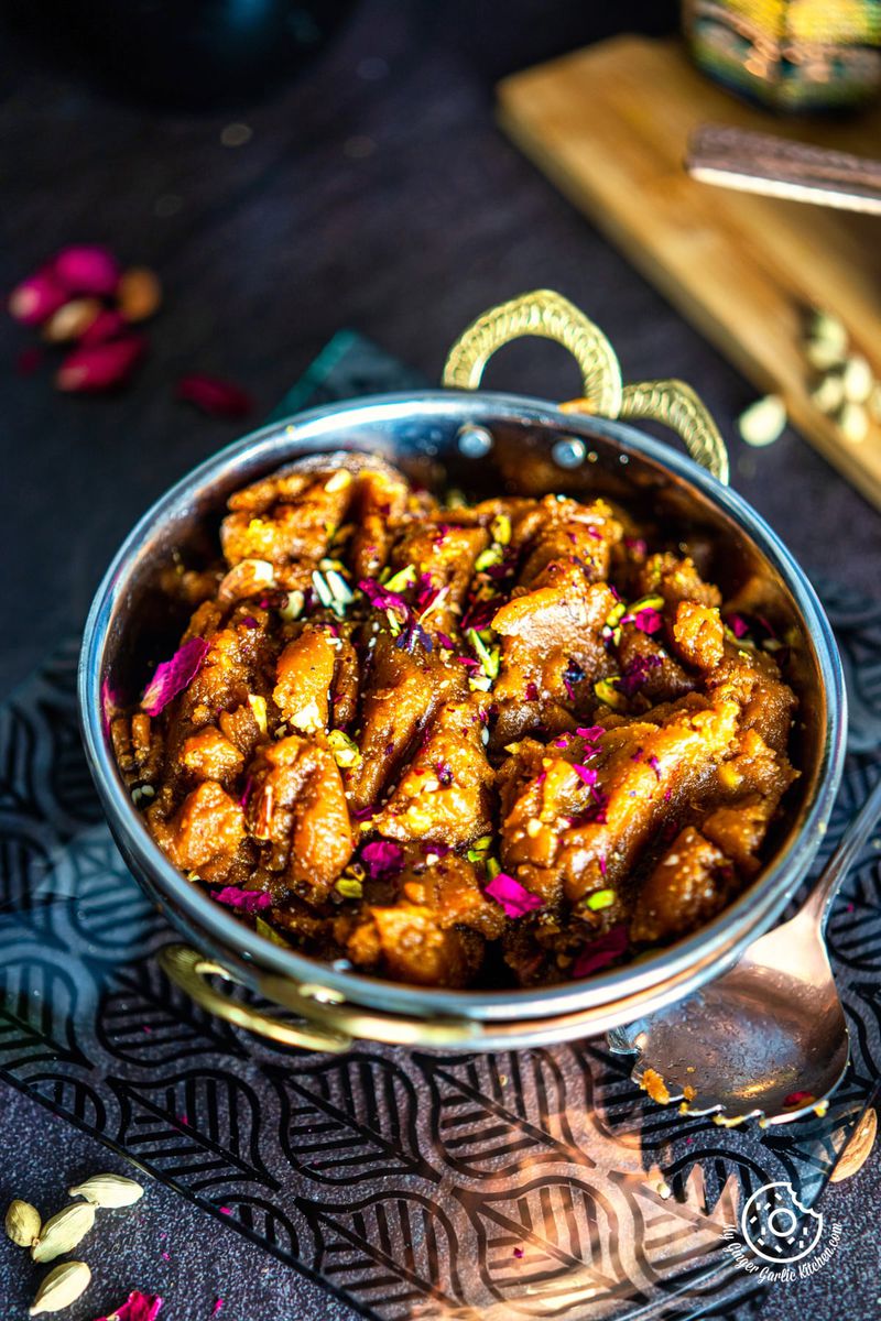 besan halwa garnished with dry fruits in a metal bowl