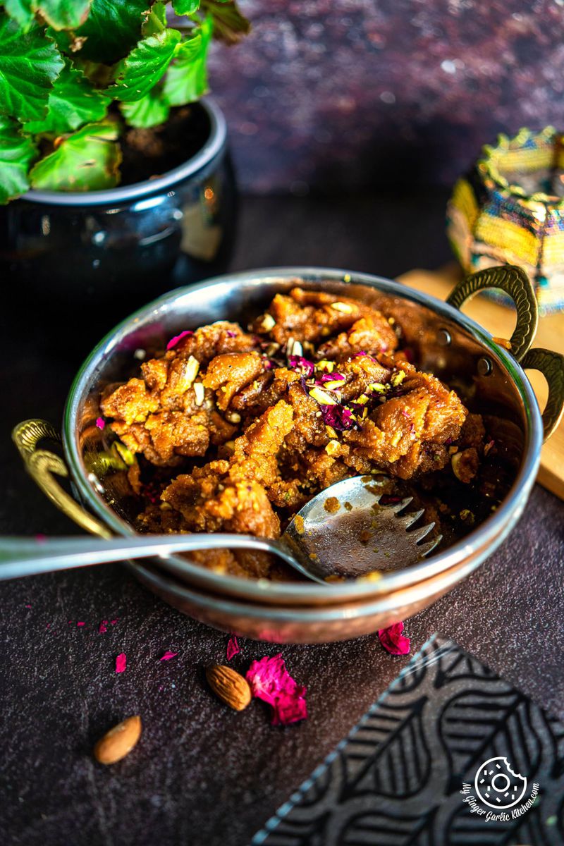  besan halwa in a copper kadai with a spoon