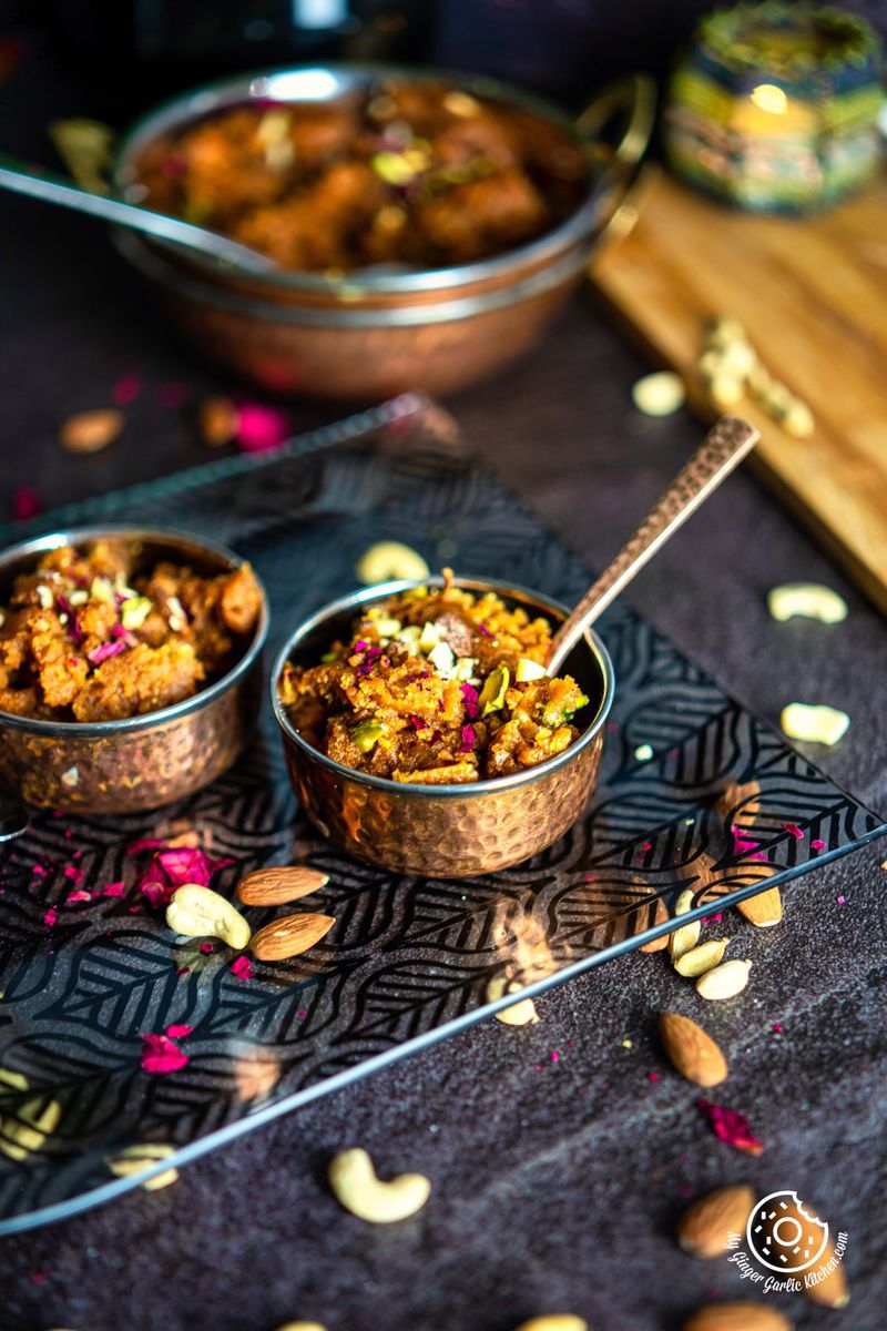 one small copper bowl filled besan halwa with a one more bowl and a bowl in the background