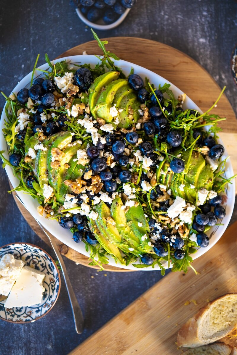 Top-down view of blueberry avocado salad with arugula, walnuts, blueberries, and lemon vinaigrette