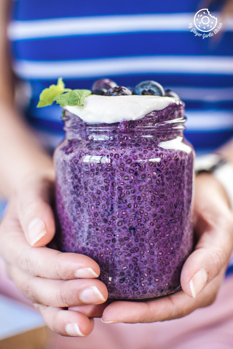 a girl holding bluberry chia seed pudding jar