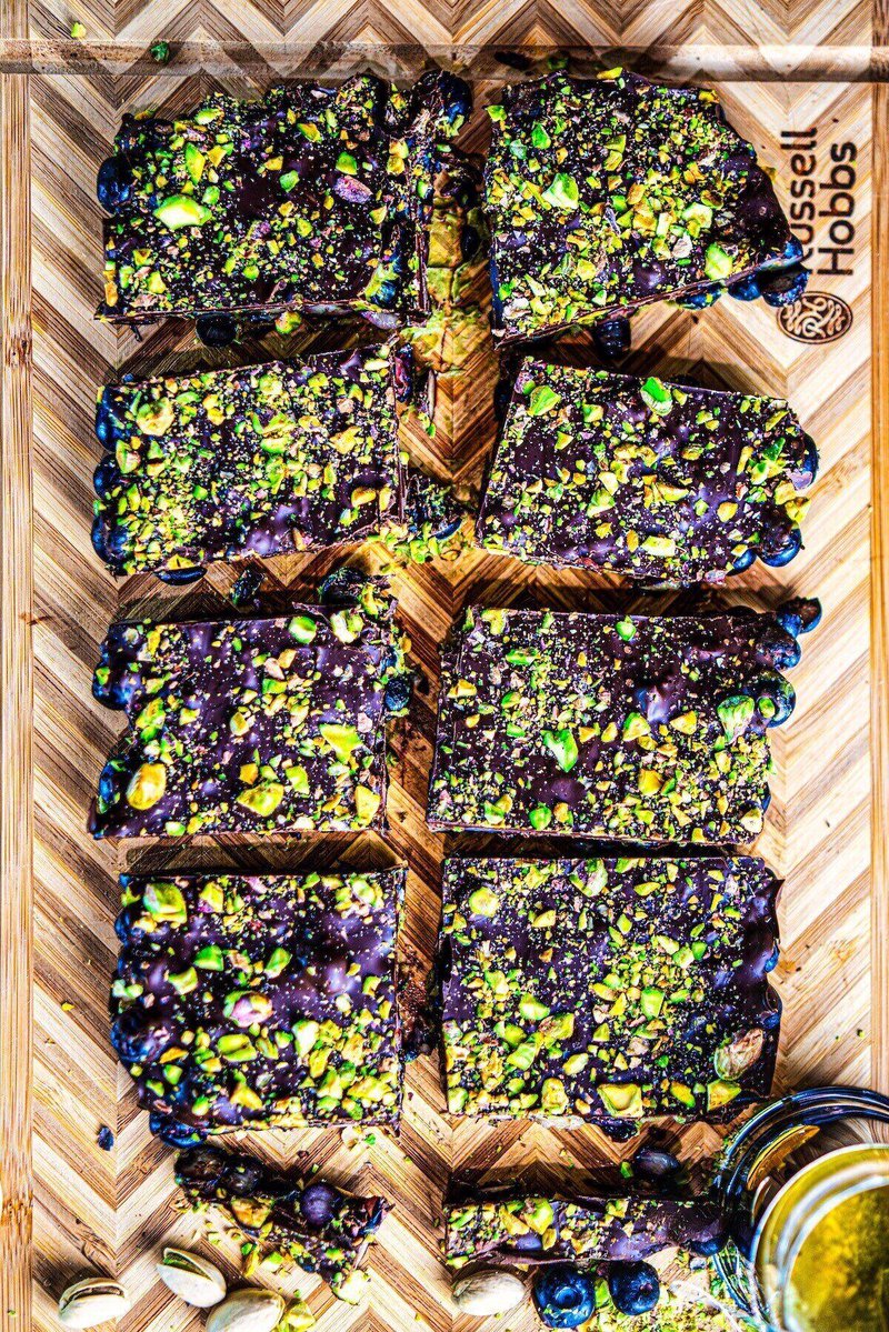Blueberry Pistachio Chocolate Bark recipe cut into bars with layers of fresh blueberries, pistachio butter, dark chocolate, and chopped pistachios.