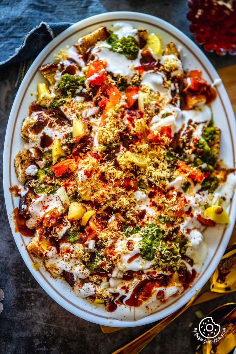 overhead closeup shot of bread dahi chaat served in a white oval shaped plate