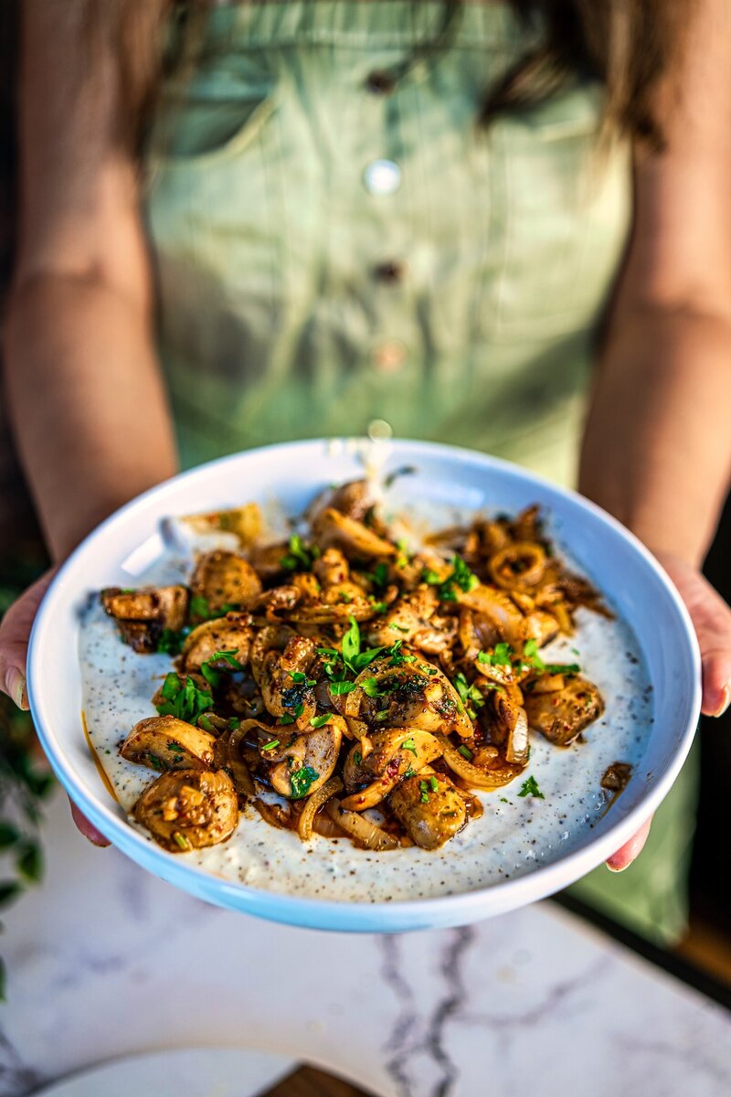 Close-up of sautéed garlic butter mushrooms with onions and herbs in a white serving bowl