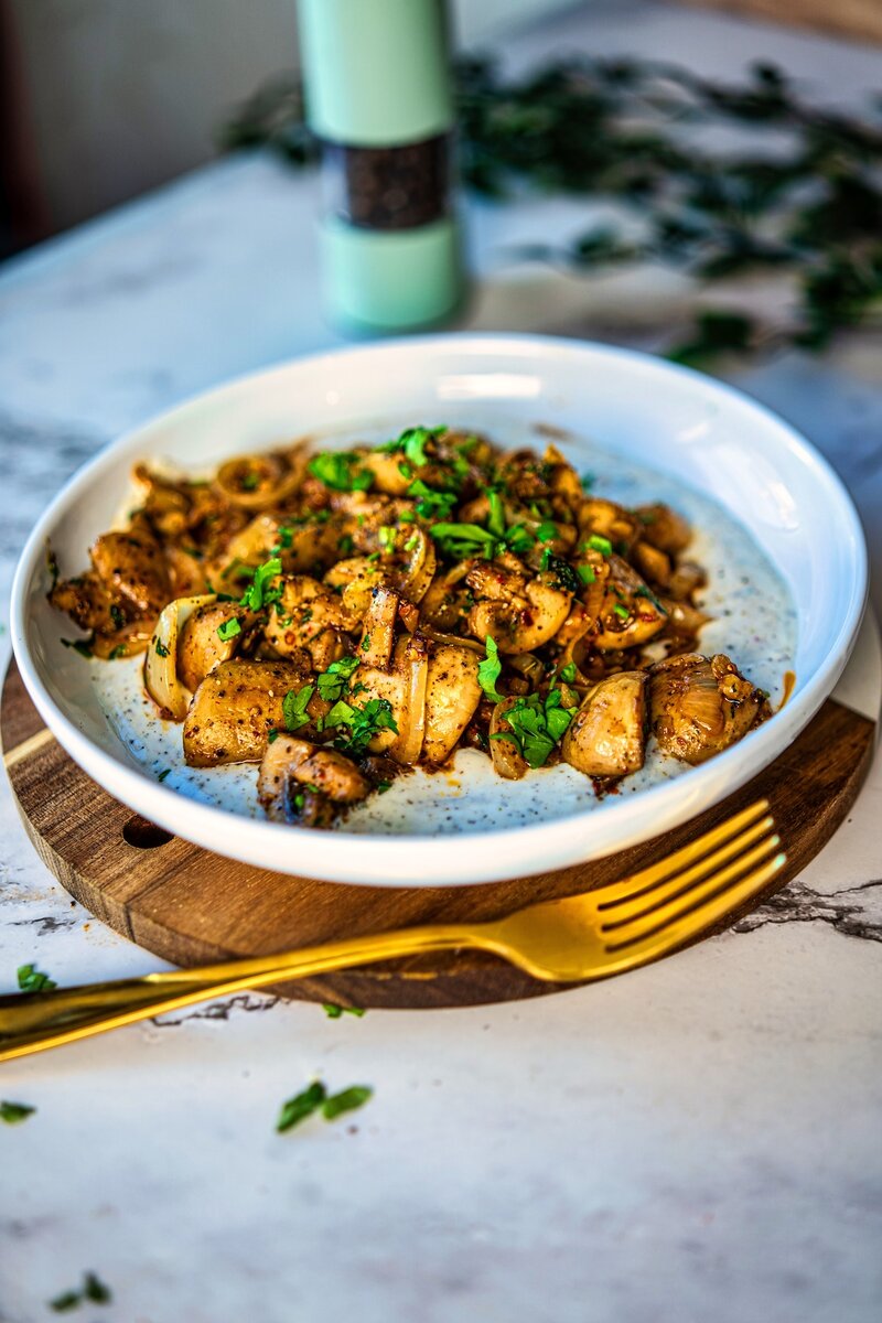 Restaurant style butter garlic mushrooms topped with parsley on creamy yogurt base