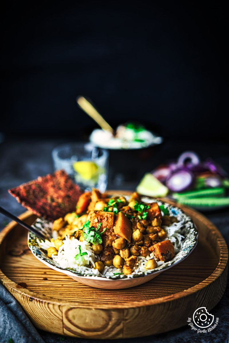 image of butternut squash chickpea curry served in a white bowl over wooden board