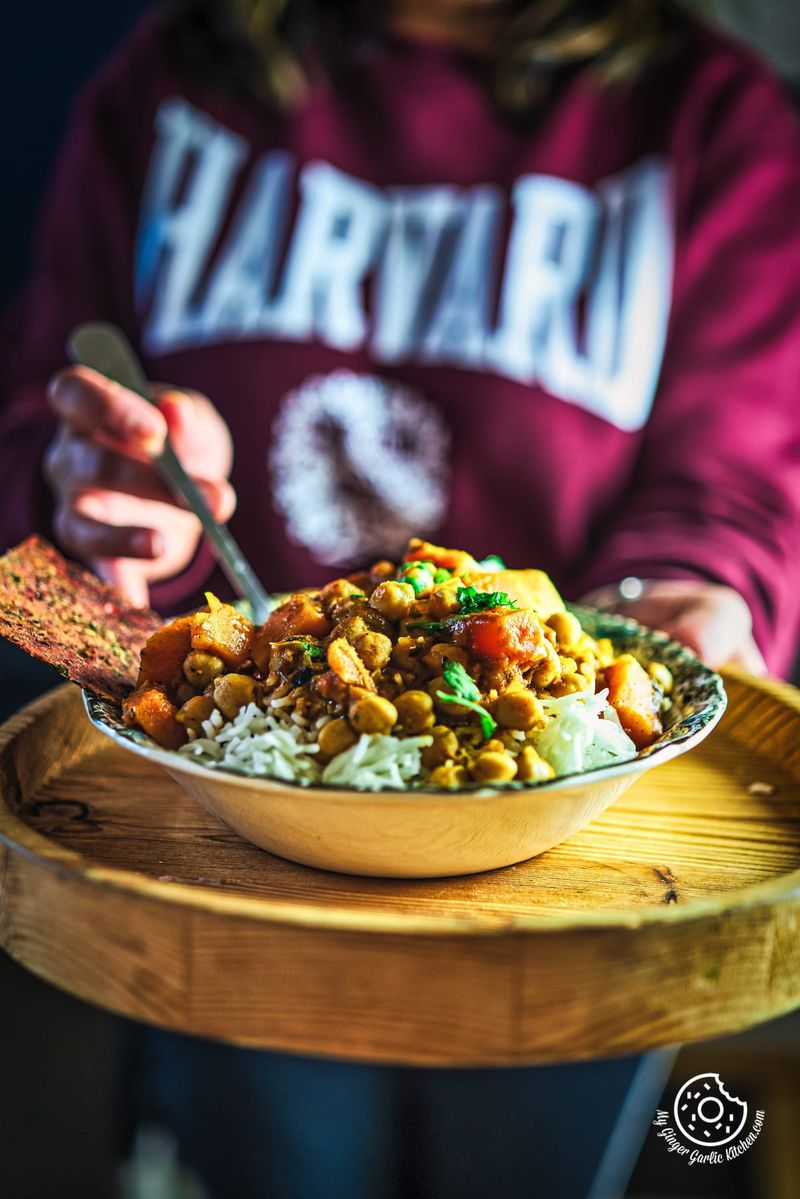 a person holding a bowl of butternut squash chickpea curry