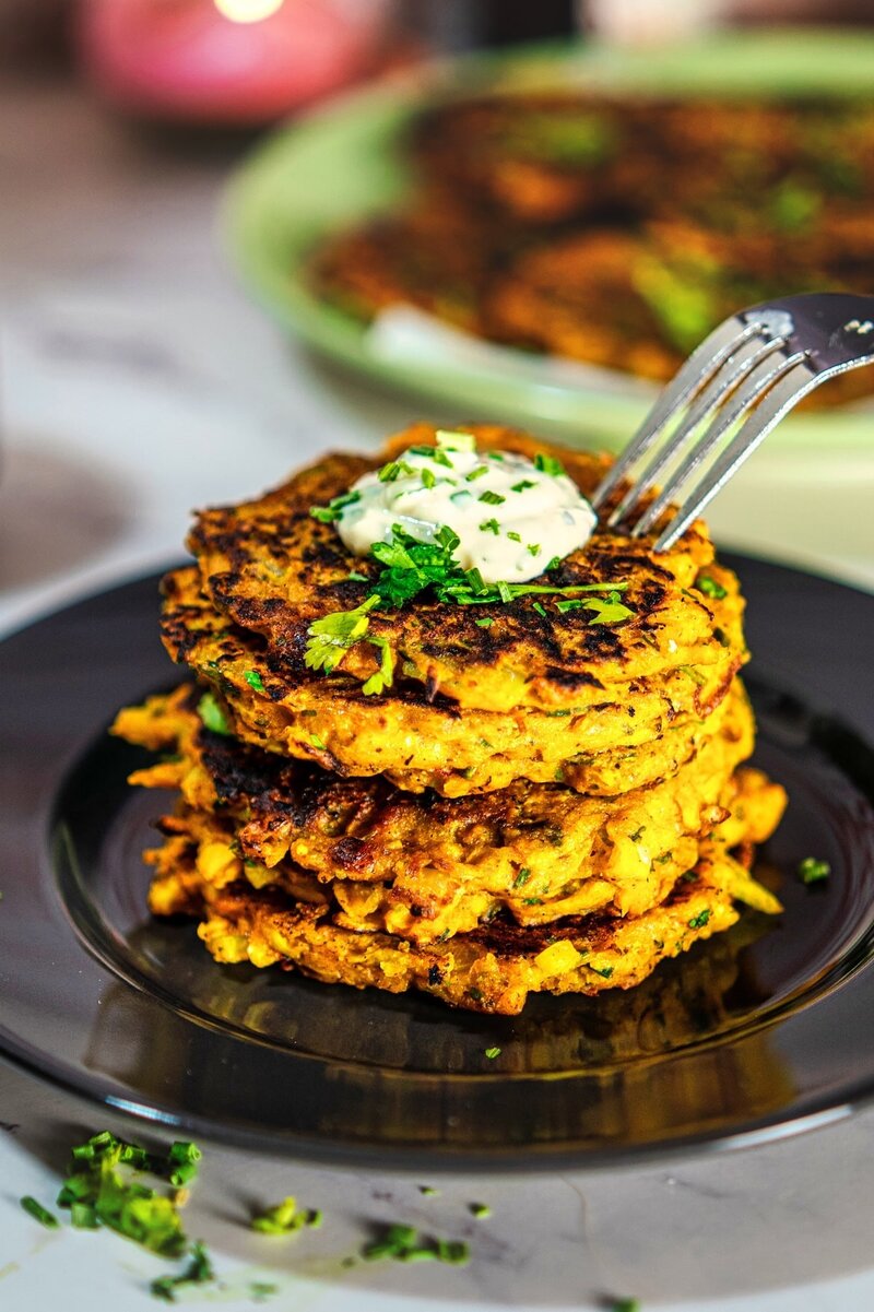 Close-up of crispy butternut squash fritters with creamy mustard yogurt dip and fresh herbs