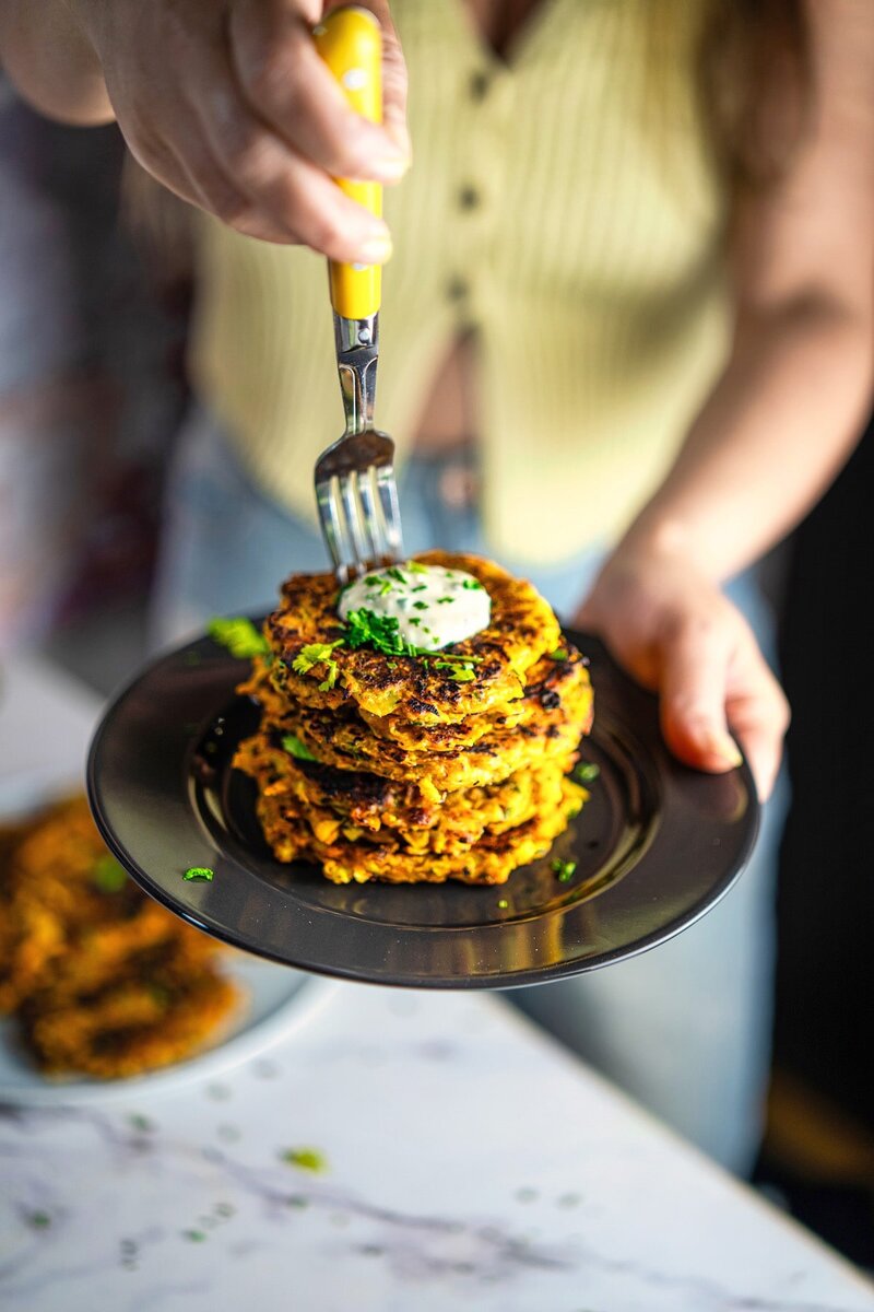 Plate of golden vegan butternut squash fritters garnished with fresh coriander and chives