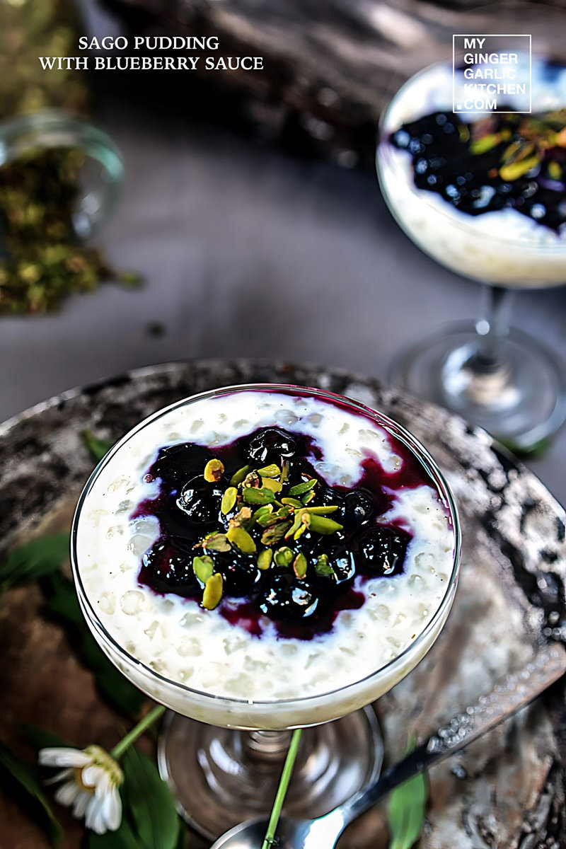 a sago pudding with blueberry sauce and pistas in a glass