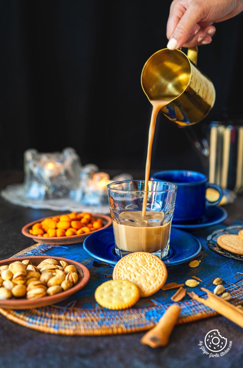a cup of caramel chai is being poured into a bowl with nuts and cookies on the side