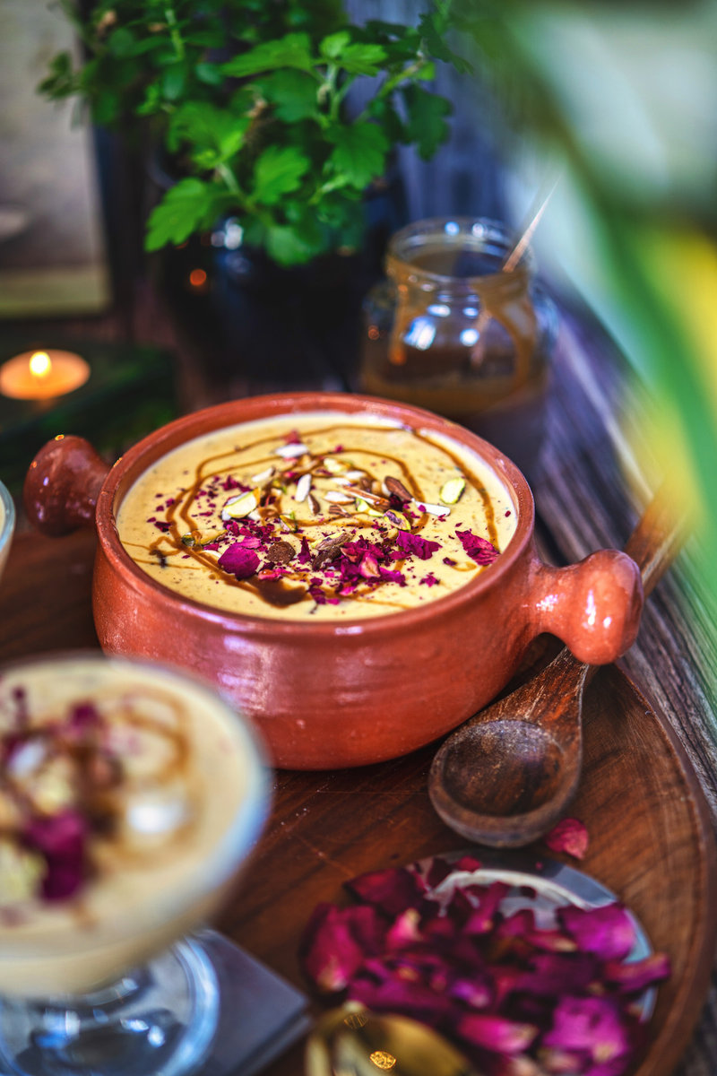 A rustic setting featuring caramel kheer served in a clay pot with background ambiance.