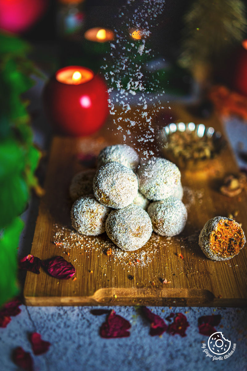Coconut powder sprinkling over a stack of raw carrot cake balls