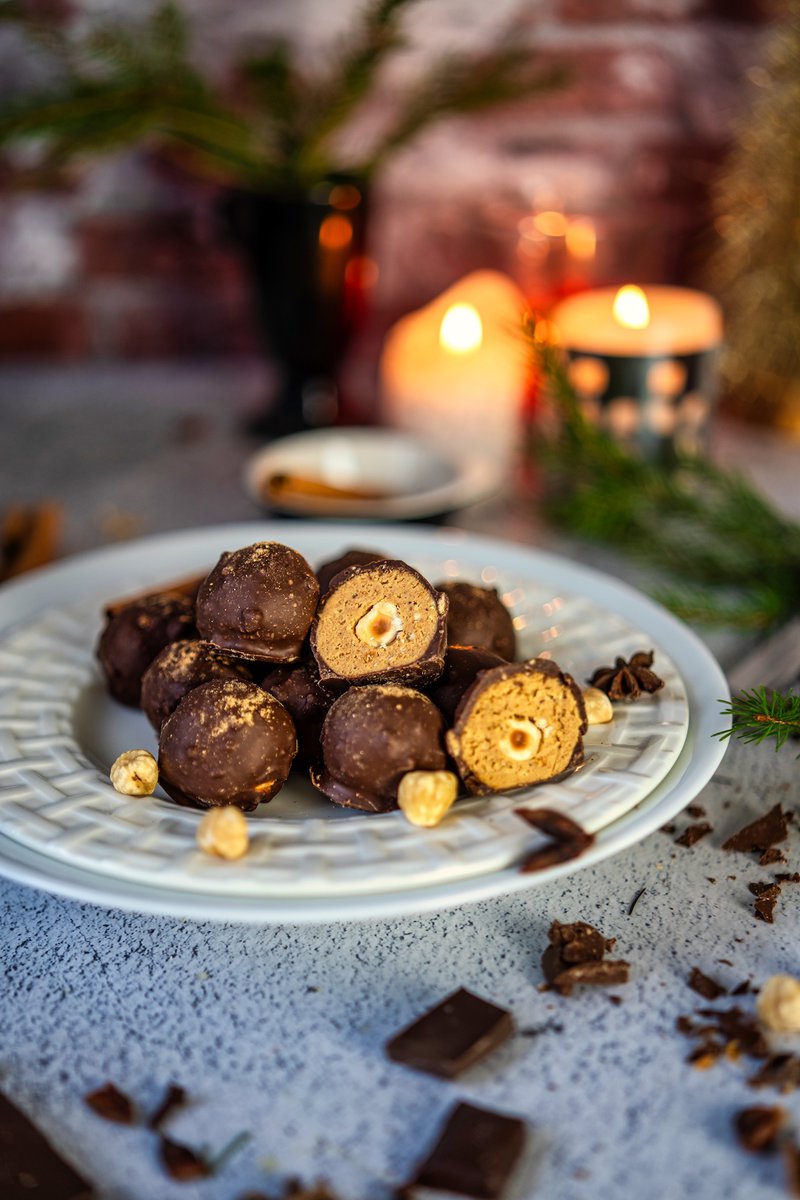 Chocolate chai truffles cut in half revealing hazelnut centers on a white plate with holiday decor.