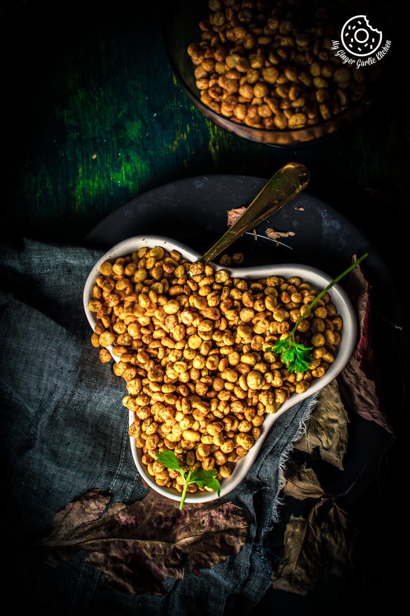 there is a bowl of chana dal namkeen on a cloth with a golden spoon